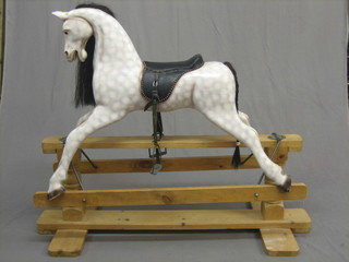A  20th  Century  dapple  grey rocking horse,  raised  on  a  pine swing stand
