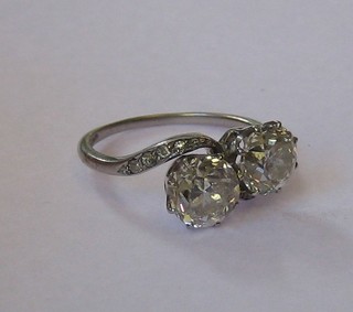 A lady's platinum cross over dress ring set 2 large diamonds supported by 8 small diamonds to the shoulders