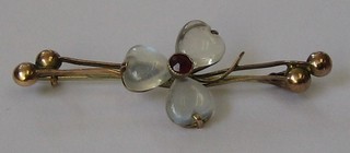 A gilt metal bar brooch decorated a clover and set moon stones and garnet