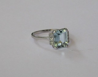 A lady's 18ct white gold dress ring set a rectangular cut aquamarine supported by diamonds to the shoulder