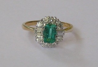 A lady's gold dress ring set a rectangular cut emerald supported by 2 baguette cut diamonds and numerous other diamonds