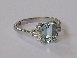 A lady's 18ct white gold dress ring set a square cut aquamarine and 2 baguette cut diamonds to the shoulders, supported by 4 diamonds