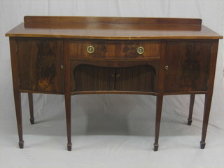 An Edwardian Georgian style mahogany serpentine fronted sideboard, fitted 1 long drawer above a cupboard enclosed by a tambour shutter, flanked by a pair of cupboards, raised on square tapering supports ending in spade feet 60"