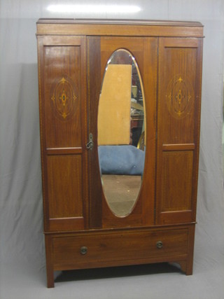 An Edwardian inlaid mahogany wardrobe with moulded cornice, enclosed by an oval bevelled plate mirrored door, the base fitted a drawer, raised on bracket feet 47" (mirror requires re-silvering)