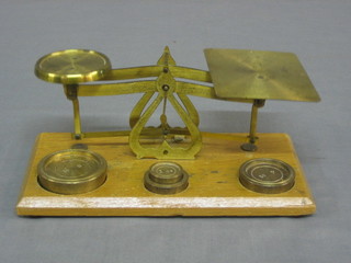 A pair of brass postage scales, raised on an oak stand complete with weights