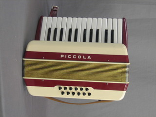 A Horner Piccol accordion with 12 buttons contained in a plastic case