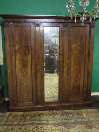 A William IV mahogany triple wardrobe with moulded cornice, the centre section fitted a plate mirror flanked by a pair of doors, raised on a platform base 81"