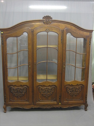 A 19th/20th Century French arch shaped oak display cabinet/bookcase, the interior fitted adjustable shelves enclosed by astragal glazed panelled doors, raised on cabriole supports 69"