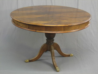 A 20th Century Georgian style oval rosewood extending dining table with concealed extra leaf, raised on pillar and tripod supports 47"