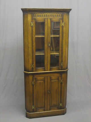 A good quality 20th Century carved oak double corner cabinet with moulded cornice and arcaded decoration, the upper section fitted adjustable shelves enclosed by glazed panelled doors, the base fitted a cupboard enclosed by a panelled door 29" wide