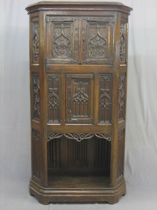 A 19th/20th Century lozenge shaped oak cabinet with moulded cornice, the upper section fitted a cupboard enclosed by panelled doors above a further cupboard enclosed by panelled doors, carved throughout and with linen fold decoration 40"