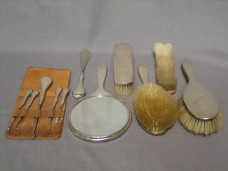 An 11 piece silver backed dressing table set comprising pair of clothes brushes, pair of hair brushes, hand mirror, shoe horn, 2 button hooks, miniature corkscrew and 2 manicure implements, Birmingham 1918 and later