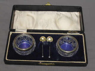 A pair of circular cut glass salts with silver rims, cased