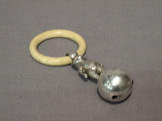 A childs silver rattle in the form of a double sided teddybear standing on a ball with bone teething ring