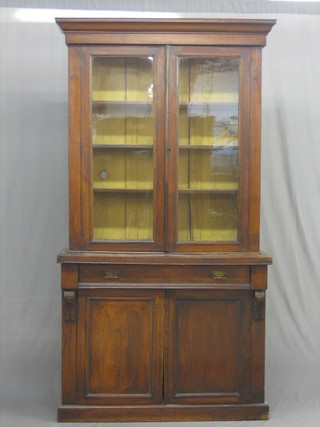 A Victorian mahogany bookcase on cabinet with moulded cornice, the upper section fitted shelves enclosed by glazed panelled doors, the base fitted 1 long drawer above a cupboard enclosed by a pair of panelled doors, raised on a platform base 41"