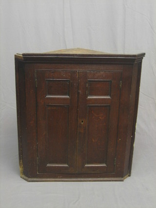 An 18th/19th Century Country oak corner cabinet with moulded cornice, fitted shelves enclosed by a panelled door 36"