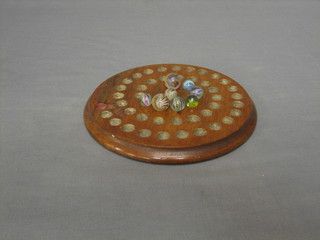 A circular wooden solitaire board together with 8 marbles