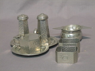 A Craftsman planished pewter tea strainer and stand, marked Craftsman Sheffield, 3 piece octagonal condiment set on a clover leaf stand and 2 pewter napkin rings