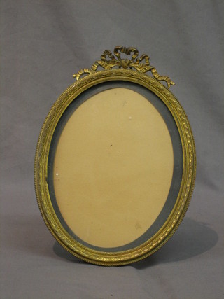 An oval gilt metal photograph frame surmounted by swags 9"