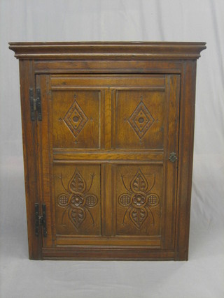 An 18th/19th Century carved oak hanging corner cabinet with moulded cornice, the interior fitted shelves enclosed by a carved panelled door 36"