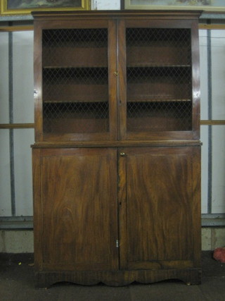 A Regency mahogany cabinet on cabinet with moulded cornice, the shelved interior enclosed by grilled panelled doors, the base fitted a cupboard enclosed by panelled doors, raised on a platform base 49"