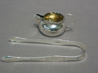 A pair of Georgian silver bright cut sugar tongs, London 1836 and a small Victorian silver cream jug (some dents)