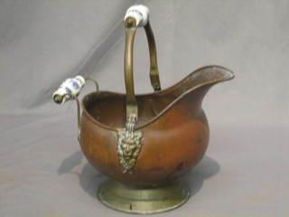 A reproduction copper helmet shaped coal scuttle with blue and white porcelain handle