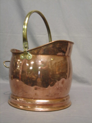 A copper helmet shaped coal scuttle with brass swing handle