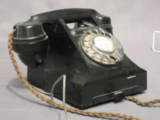 An old black Bakelite dial telephone, the base marked FWR 59/2