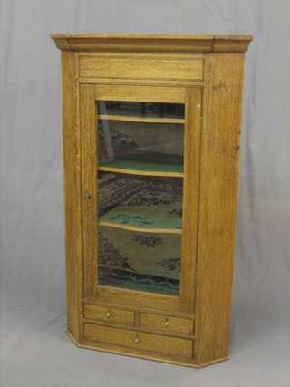 A 19th/20th Century honey oak hanging corner cabinet with moulded cornice, the interior fitted shelves enclosed by glazed panelled doors, the base fitted 2 short drawers and 1 long drawer 30"