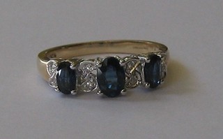 A lady's 9ct gold dress ring set 3 oval cut sapphires supported by diamonds