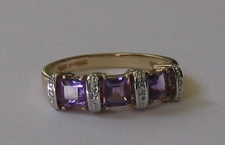A lady's 9ct yellow gold dress ring set 3 square cut amethysts supported by diamonds