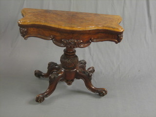 A Victorian figured walnut card table of serpentine outline, raised on a carved column and tripod base 45"