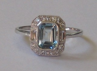 A lady's 18ct white gold dress ring set a rectangular cut aquamarine with 2 baguette cut diamonds to the shoulders, surrounded by numerous other diamonds