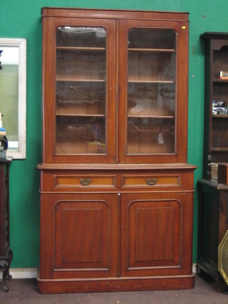 A  Victorian  mahogany bookcase on cabinet,  the  upper  section with  moulded  cornice,  the  shelved  interior  enclosed  by  arch shaped  panelled doors, the base fitted 2 drawers above  a  double cupboard, raised on a platform base 47"