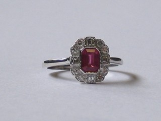 A  lady's  18ct  white gold dress ring set a  rectangular  cut  ruby supported by 4 baguette cut diamonds and surrounded by 10 other diamonds