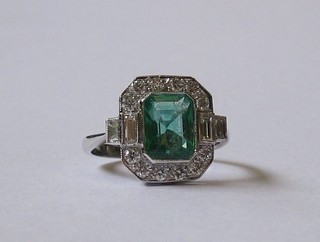 A  lady's white gold dress ring set a rectangular cut emerald,  the shoulders  set  4  baguette  cut diamonds  and  surrounded  by  12 diamonds approx. 0.55/1.70ct