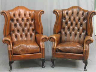 A pair of Georgian style mahogany framed armchairs upholstered in brown leather, raised on cabriole supports