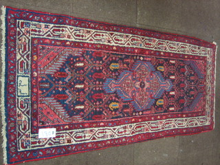 An Eastern red ground rug with central geometric medallion  73" x 32", signed