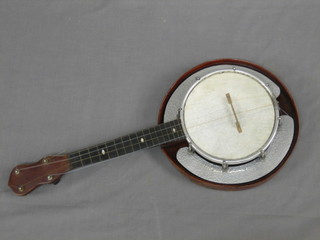 An unusual 4 stringed banjo the 8" circular drum with 8 bolts and having  planished  metal  side  pieces  with  solid  wooden   back