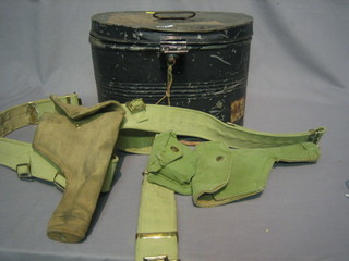 An  old  circular  metal  hatbox, a pair of  wading  gaiters  and  2 webbing belts with holsters