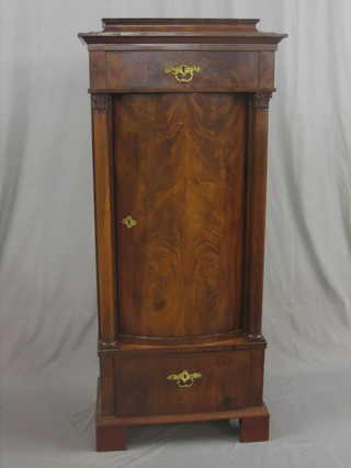 A  19th  Century  Biedermeier  cabinet,  the  upper  section  with moulded top  fitted a drawer, the base fitted a cupboard  enclosed  by  a bow front panelled door, flanked by a pair of columns,  the base fitted a drawer and raised on bracket feet 26"