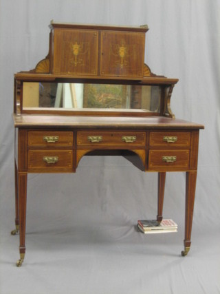 An  Edwardian  inlaid  mahogany  writing  table  with  red   inset  tooled leather writing surface, the  raised back with pierced  brass three-quarter  gallery  above  a  cupboard  enclosed  by   panelled doors,  the  base  fitted  1 long and 4  short  drawers,  raised  on square tapering supports 39"