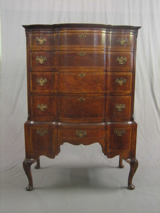 A  Queen Anne style figured walnut chest on stand  of  serpentine outline,  having a crossbanded top and fitted 4 long  drawers,  the  base  fitted  3 short drawers and raised on cabriole  supports  36"