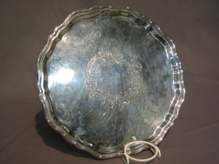 A  circular  silver plated salver with ribbon border  and  engraved decoration, raised on 3 scrolled feet 12"