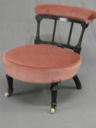 A  Victorian ebonised nursing chair upholstered in pink  material, raised on turned and fluted supports
