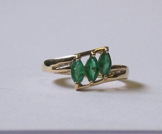 A lady's 9ct gold dress ring set 3 oval cut emeralds supported by diamonds