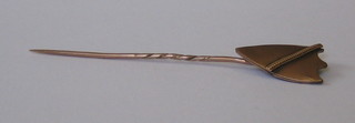 A gold shield shaped stick pin