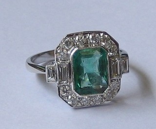 A  lady's white gold dress ring set a rectangular cut emerald,  the shoulders  set  4  baguette  cut diamonds  and  surrounded  by  12  diamonds approx. 0.55/1.70ct