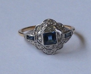 A  lady's  18ct  yellow gold dress ring set a  square  cut  sapphire supported   by   2  baguette  cut  sapphires   and   surrounded   by  numerous diamonds